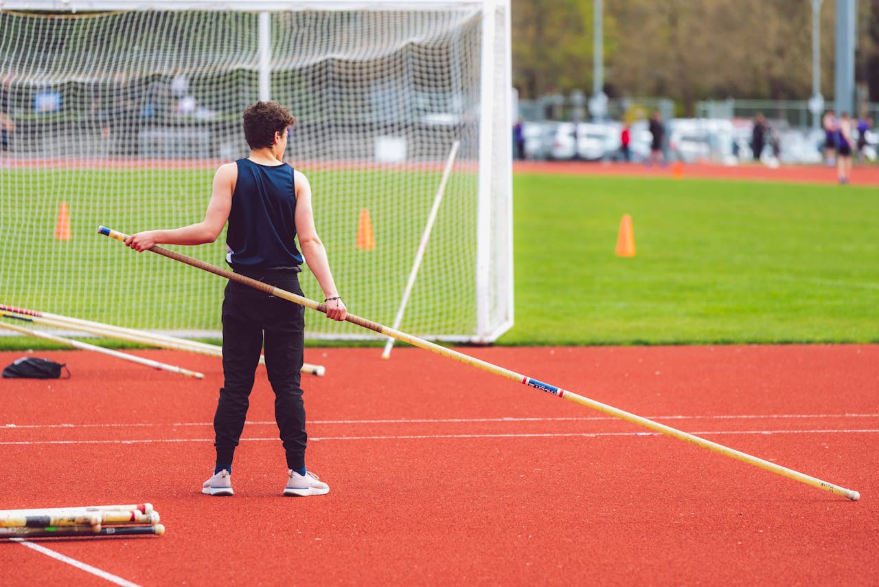 Young athlete holding pole vault preparing on field during competition.